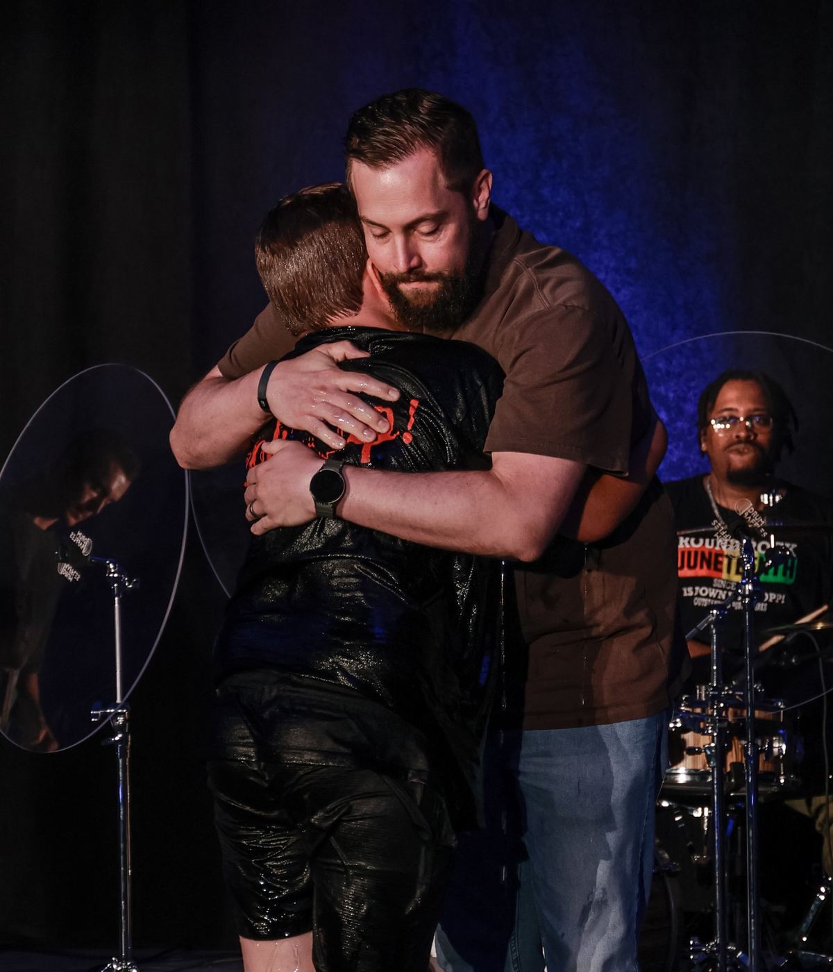 A man hugging someone soaking wet, just out of the baptism tank
