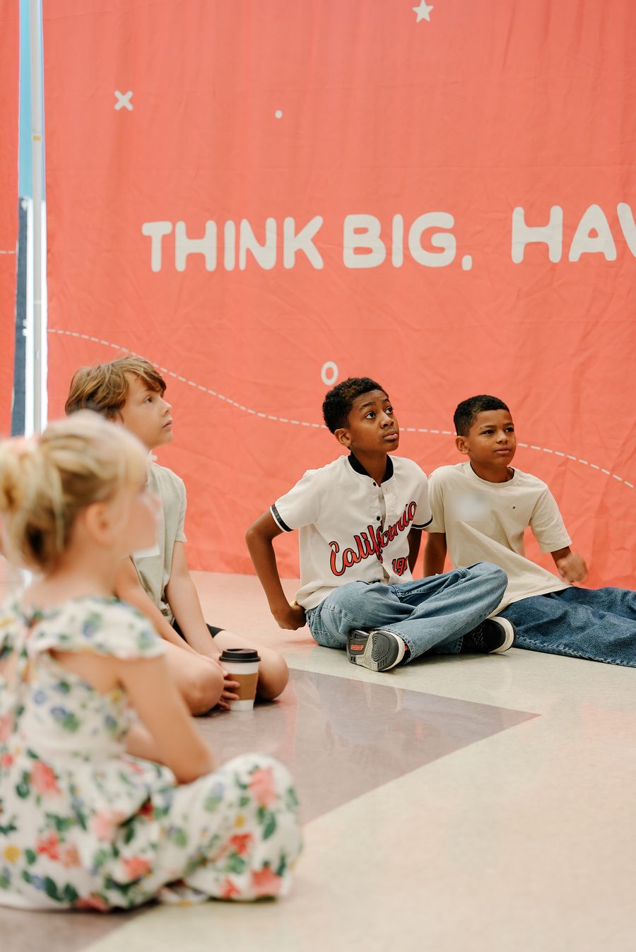 Elementary kids sitting on the floor, looking up and listening