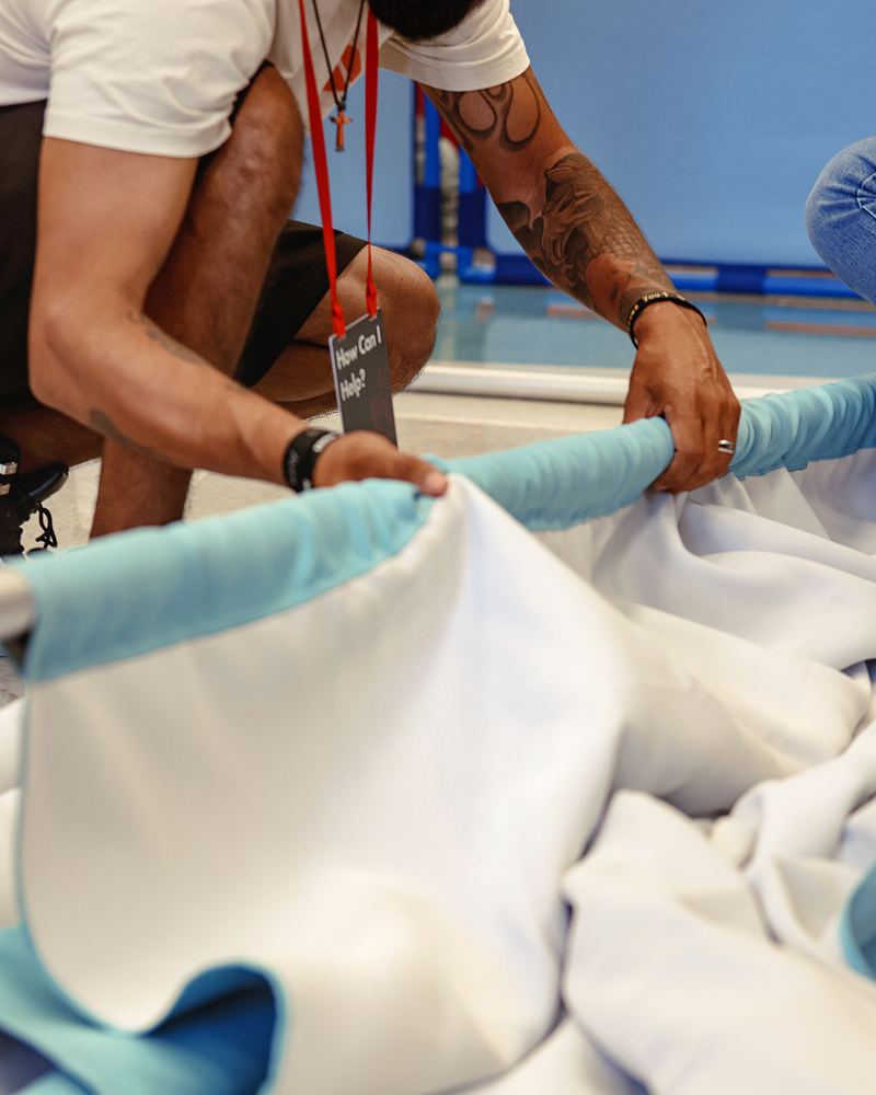 A volunteer with a lanyard pulling a curtain onto its frame
