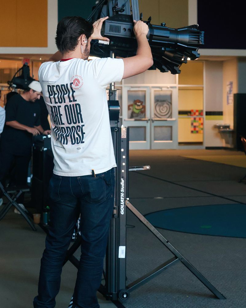 A volunteer in a People Are Our Purpose shirt adjusting a stage light