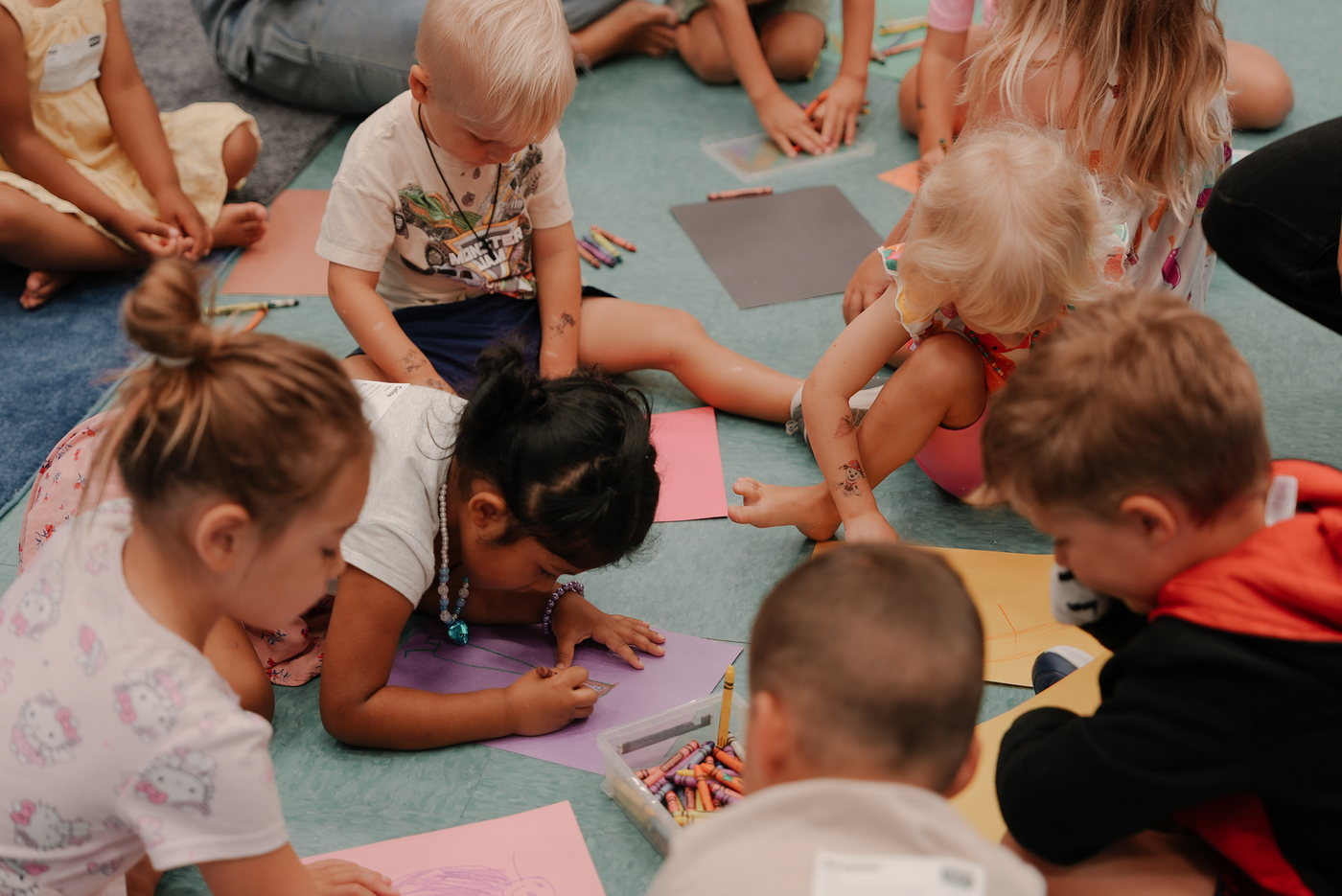 Kids coloring together on the floor in Axiom Kids