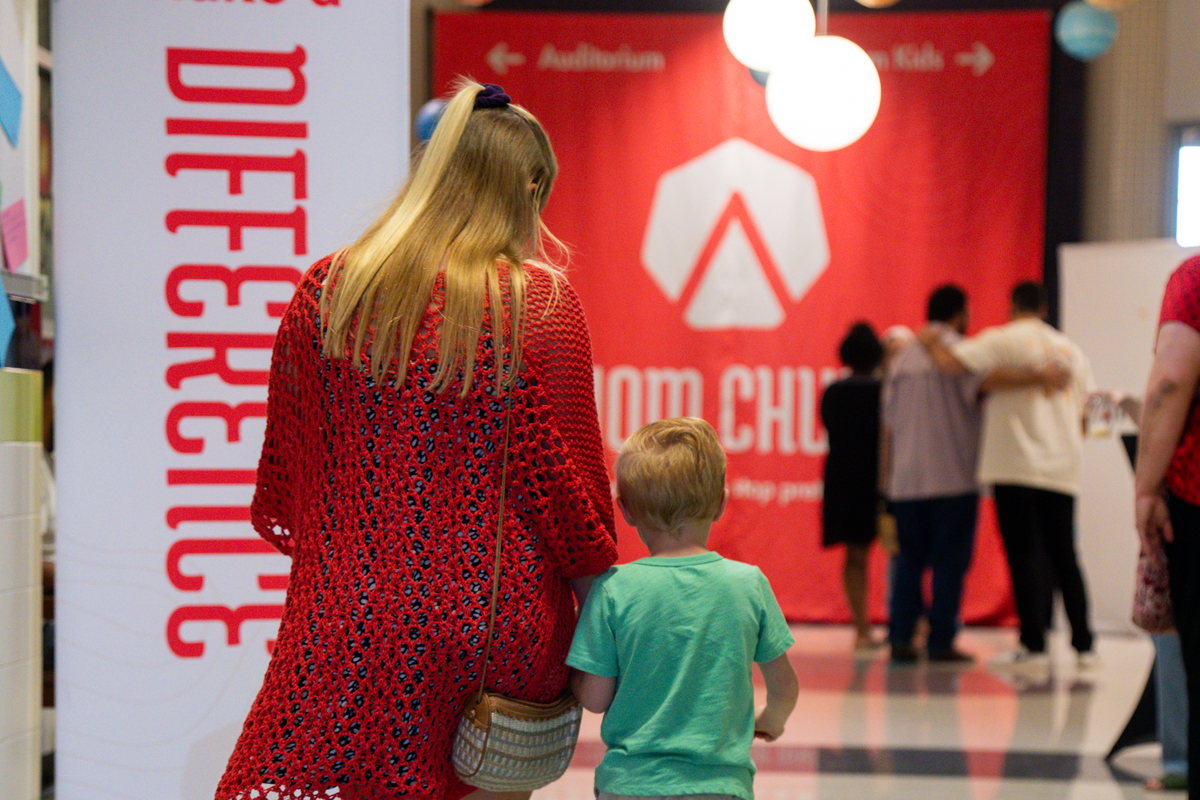 A mom and her son walking into the lobby toward the Axiom Church banner