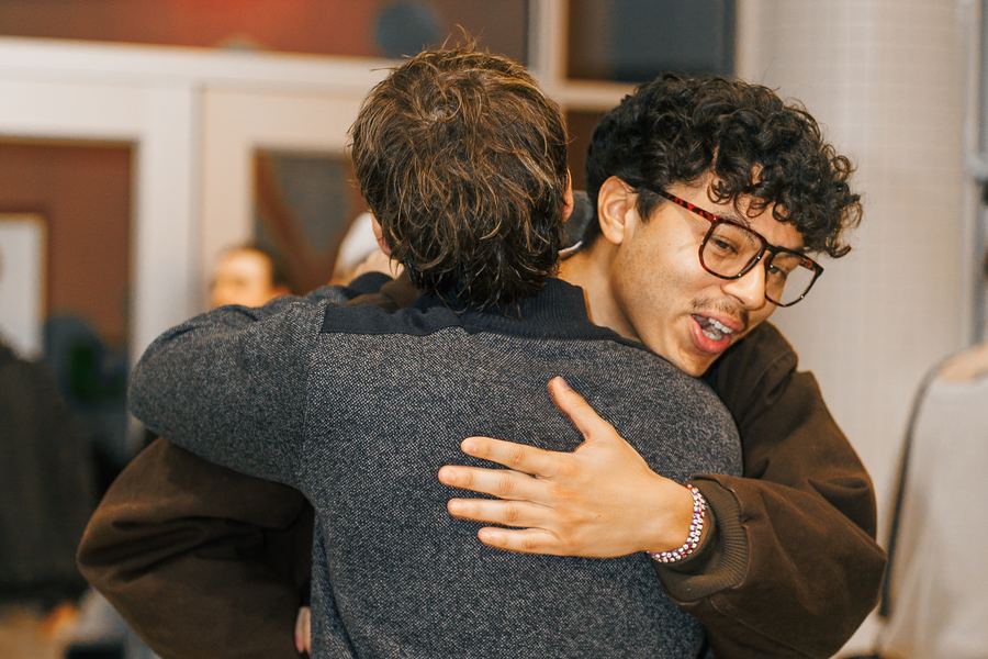 Two guys hugging in the lobby, one with his arm wrapped around the other's back