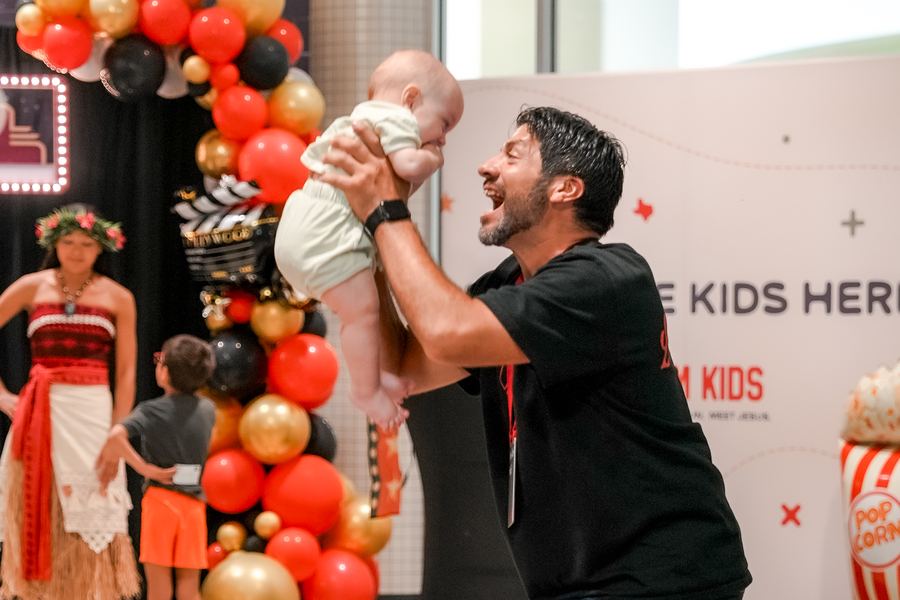 A man lifting a baby into the air, both of them laughing